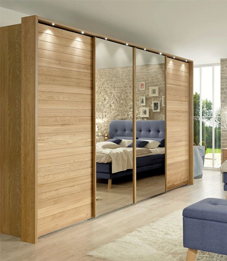 a bedroom with a bed, couch and mirrored closet doors