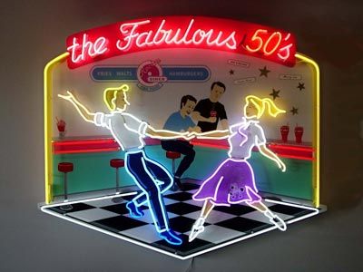 a neon sign that says the fabulous 50's with two people dancing on it