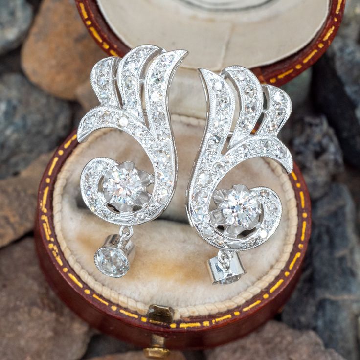 These beautiful vintage earrings are each accented with one (1) round brilliant cut diamond set into a six-prong setting, one (1) old European cut diamond set into a dangle style bezel setting and twenty-six (26), bead set, round single cut diamonds. The earrings measure 27.0mm X 11.6mm and are finished with friction style backs. Exquisite Platinum Single Cut Diamond Earrings, Exquisite Platinum Earrings With Single Cut Diamonds, Silver Art Deco Platinum Diamond Earrings, Evening Platinum Diamond Earrings With Single Cut Diamonds, Art Deco Silver Diamond Earrings In Platinum, Platinum Art Deco Earrings For Anniversary, Platinum Diamond Earrings Fine Jewelry, Art Deco Platinum Earrings For Anniversary, Exquisite Platinum Diamond Earrings