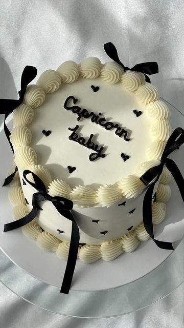 a white cake with black ribbon and congratulations written on the top is sitting on a glass plate