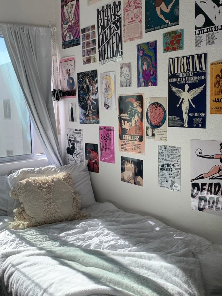 a white bed sitting next to a window covered in posters