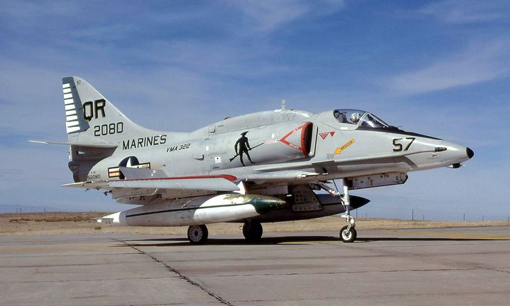 a fighter jet sitting on top of an airport tarmac under a blue cloudy sky