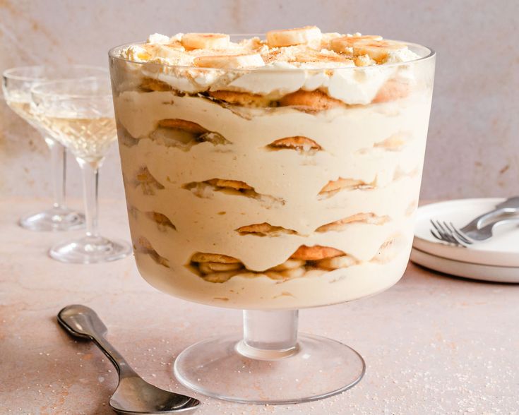 there is a dessert with white frosting and nuts on it next to two wine glasses