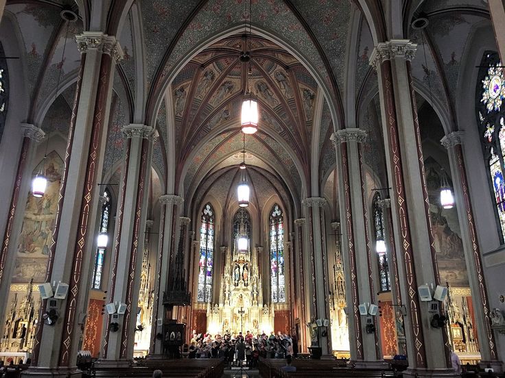 the inside of a large cathedral with pews and stained glass windows on both sides