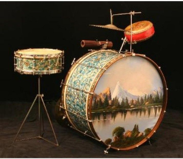 a drum with a painting on it next to a small stand and drumsticks