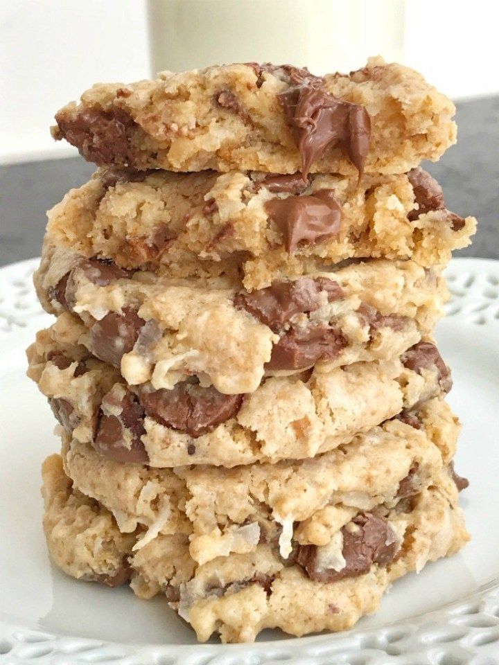 chocolate chip cookies stacked on top of each other with a glass of milk in the background