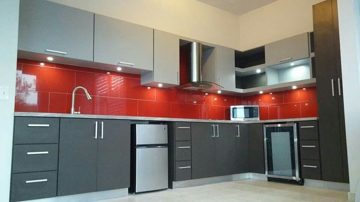 a kitchen with grey cabinets and red backsplash