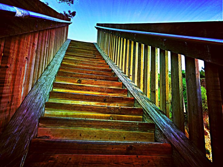 a wooden staircase going up to the top of a building with blue sky in background