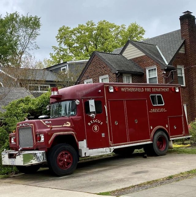 an old fire truck is parked in front of a brick house on a residential street