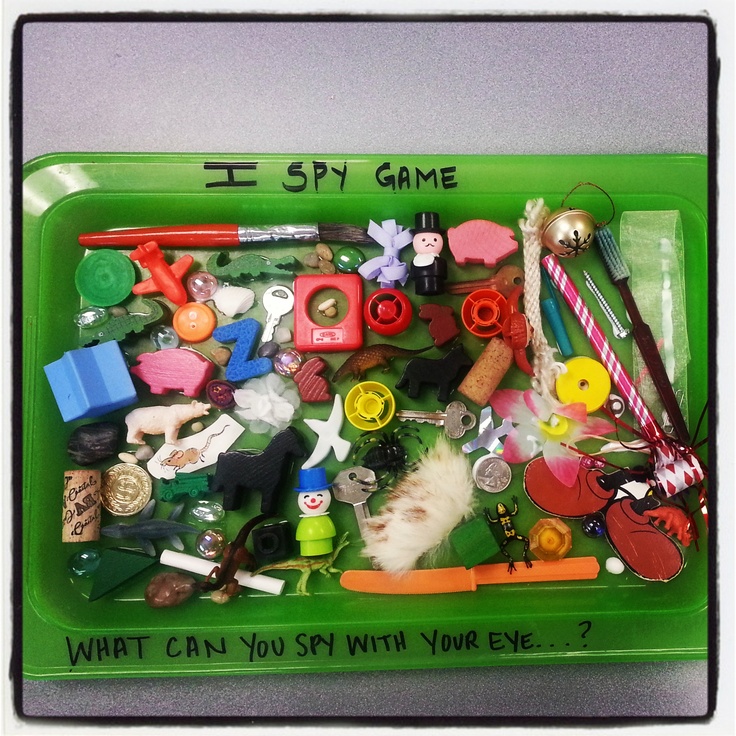 a green tray filled with lots of toys and writing on the side that says, i spy game what can you say with your eye?