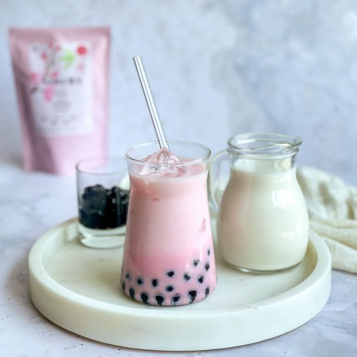 a drink on a plate next to two jars and spoons with some liquid in them