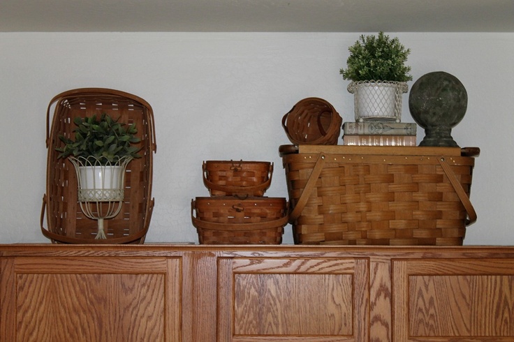 some baskets and plants are sitting on top of a cabinet