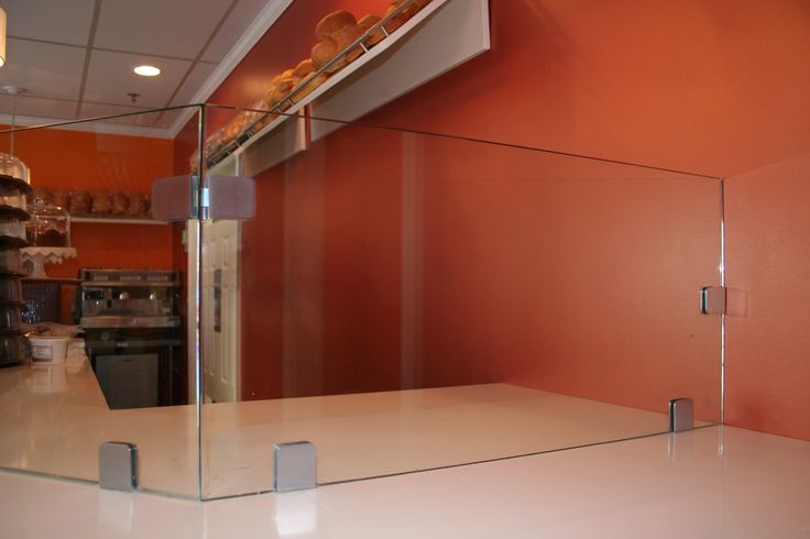 an empty counter in front of a red wall with shelves and pans on it