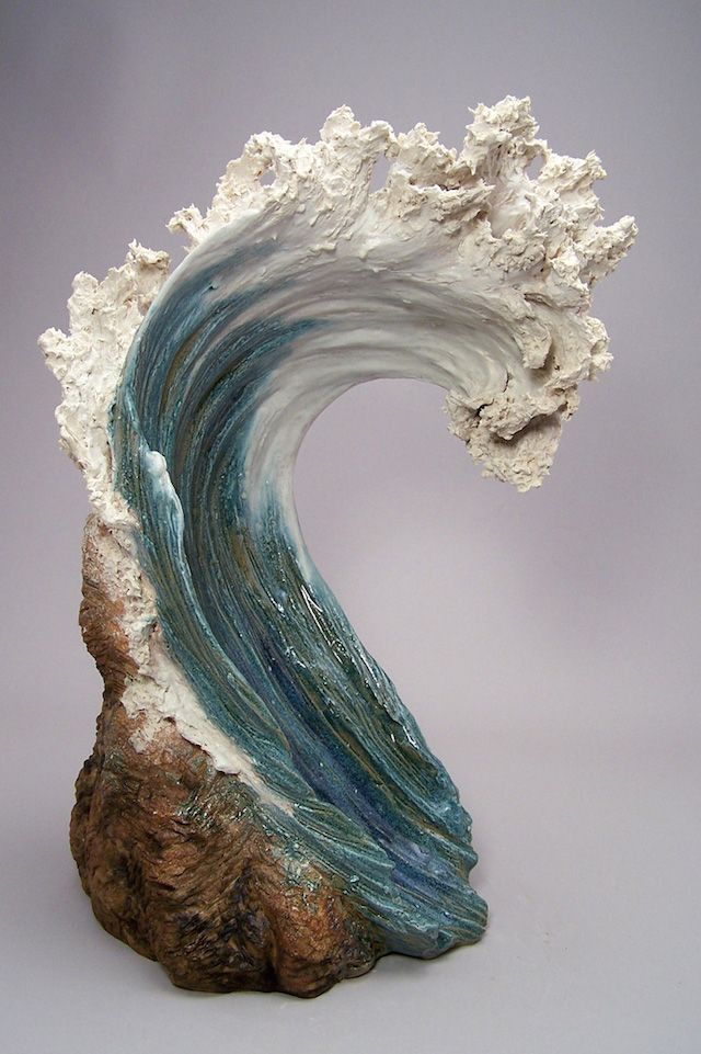 a sculpture of a wave on top of a rock with blue and white waves coming out of it