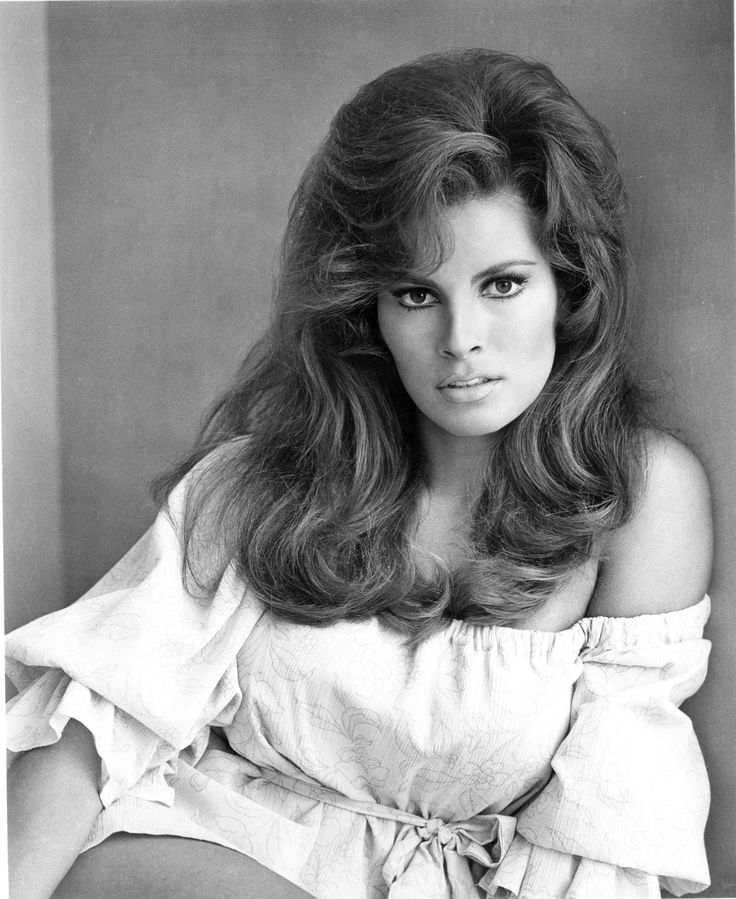 an old black and white photo of a woman with long hair wearing a top that has ruffles on it