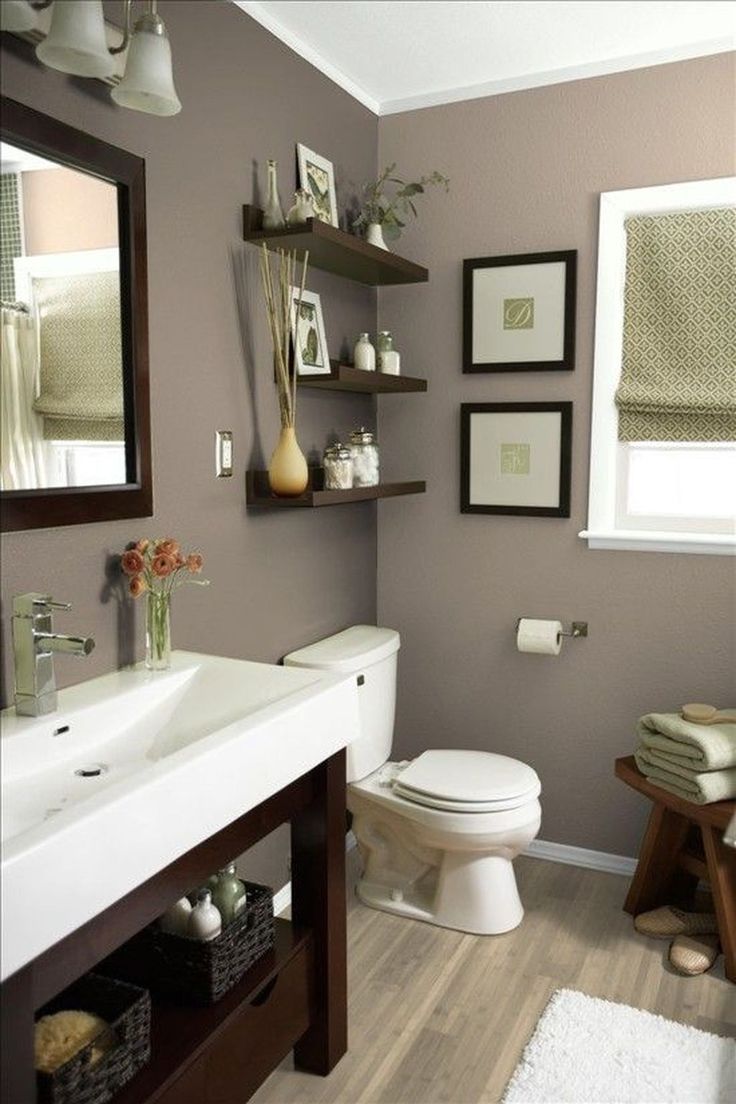 a white toilet sitting under a bathroom mirror next to a sink and a wooden table