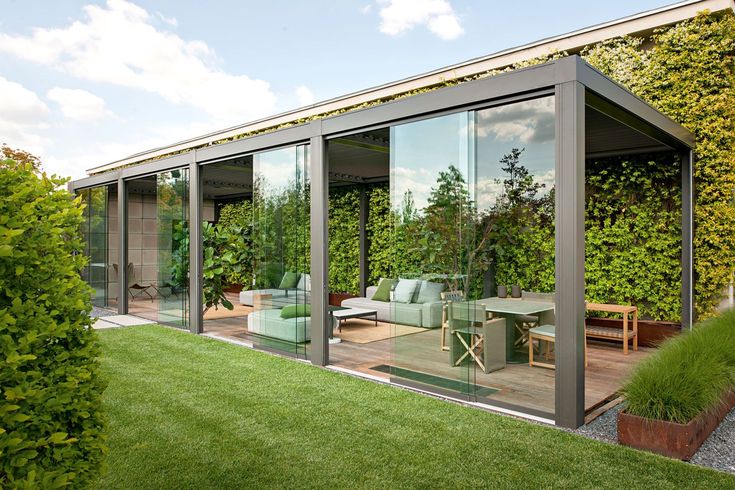 an outdoor living area with sliding glass doors and green plants on the side of it