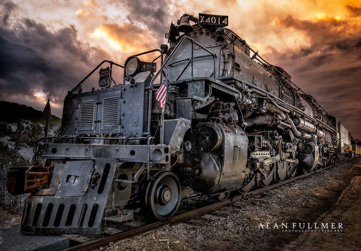 an old train engine sitting on the tracks under a cloudy sky with clouds in the background