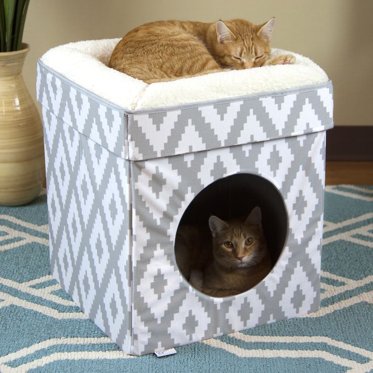 a cat laying on top of a gray and white cube shaped pet house with its eyes closed