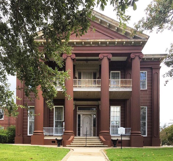 an old brick building with columns on the front and stairs to the second floor is shown