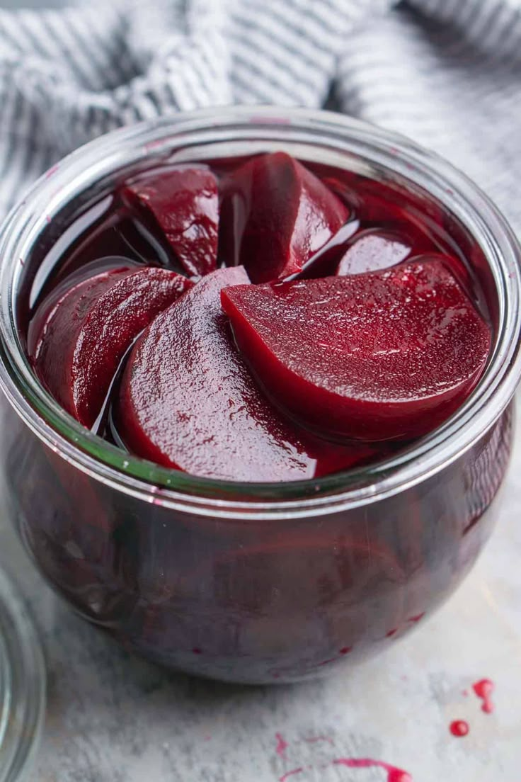 a glass jar filled with beets on top of a table