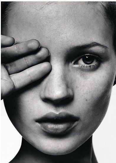 a black and white photo of a woman holding her hand to her face with one eye