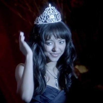 a woman wearing a tiara and waving at the camera with her hand in the air