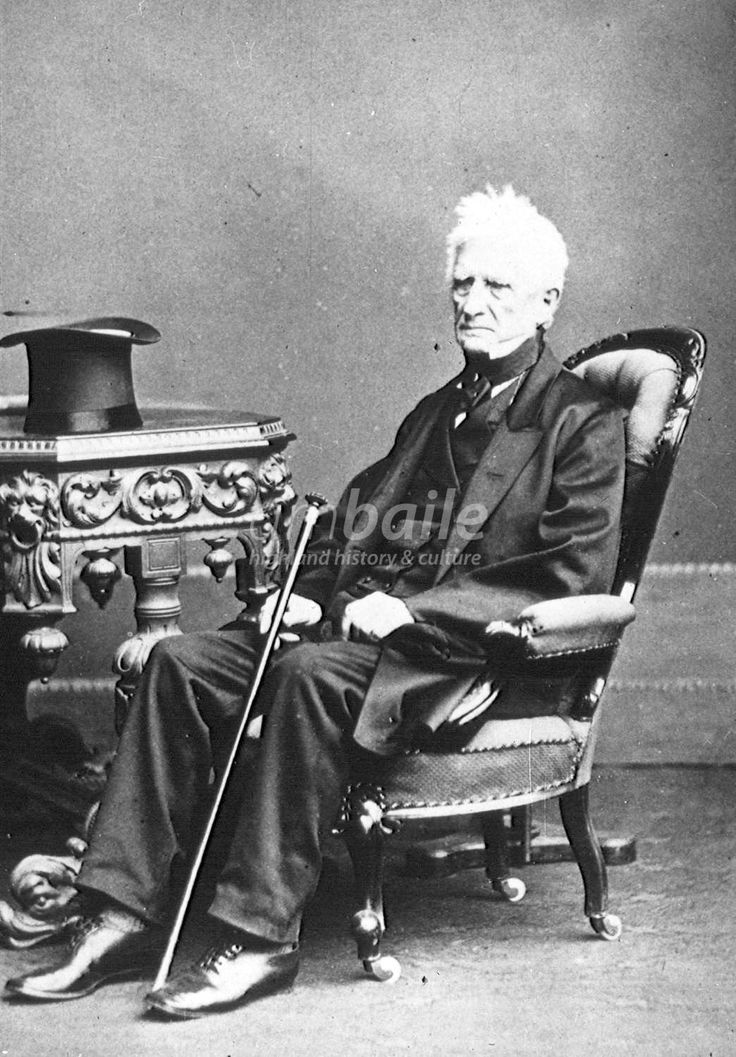 an old black and white photo of a man sitting in a chair with a cane