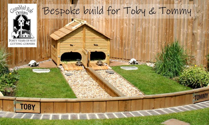 a dog house built into the side of a fenced in area with grass and rocks