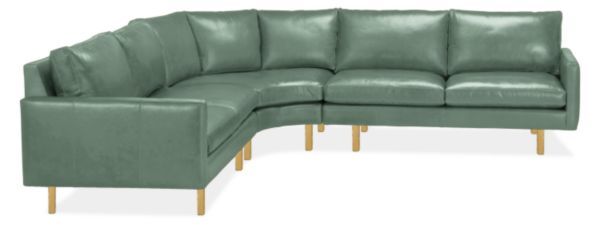 a green leather sectional sofa with wooden legs