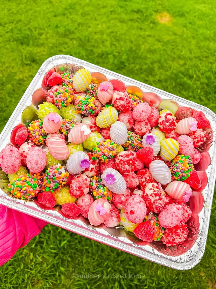 a tray filled with lots of different colored sprinkles on top of green grass