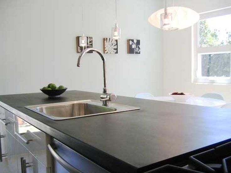 a modern kitchen with stainless steel appliances and black counter tops, along with white walls