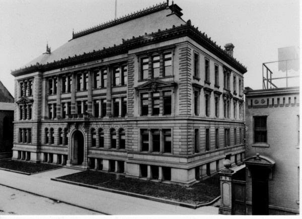 an old black and white photo of a building in the middle of town, with many windows