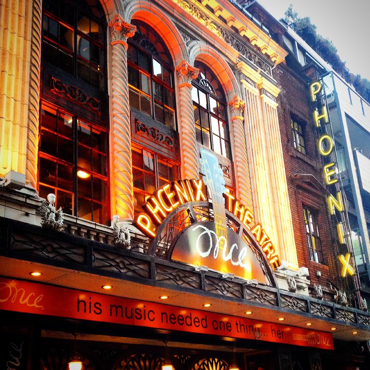 an old theater building with neon lights on the front and side of it's entrance