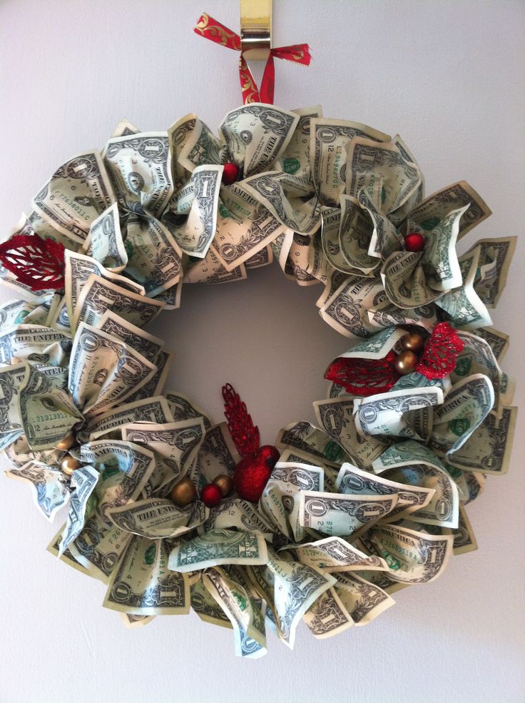 a wreath made out of dollar bills hanging on a wall with a red ribbon around it