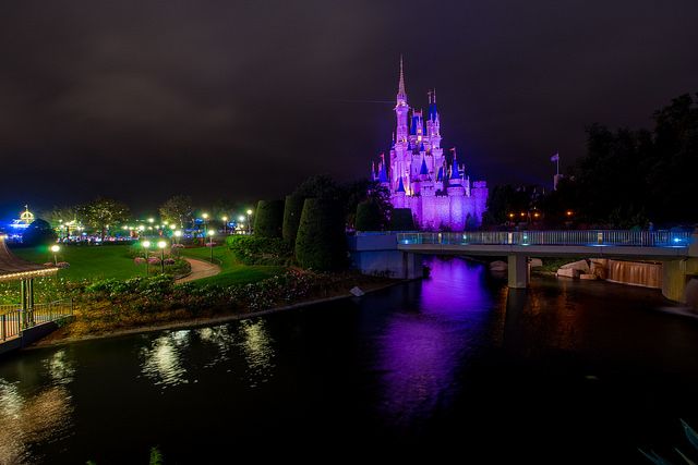 a castle lit up at night next to a river