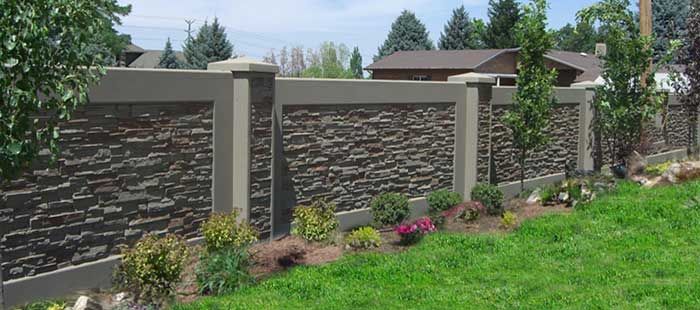 a stone fence in the middle of a green yard