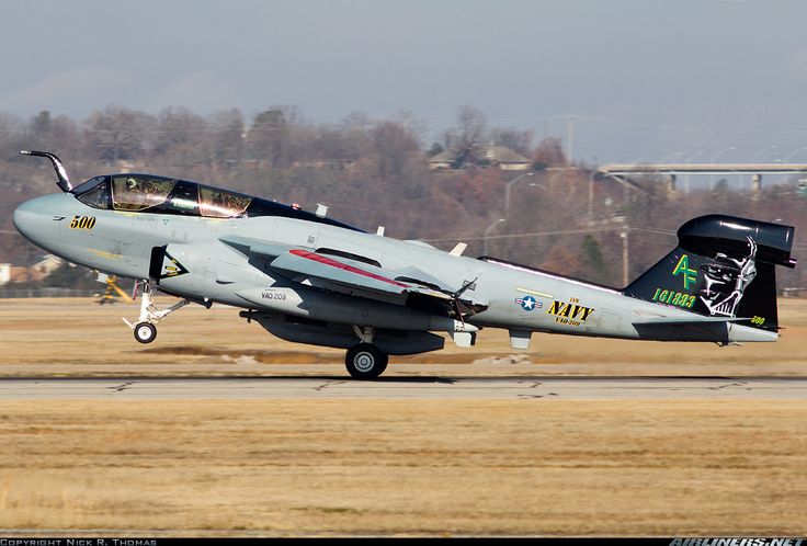 a fighter jet taking off from an airport runway with trees in the backgroud