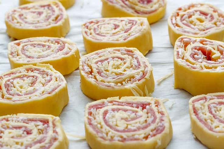 many different types of pastries are arranged on a sheet of wax paper and ready to be eaten