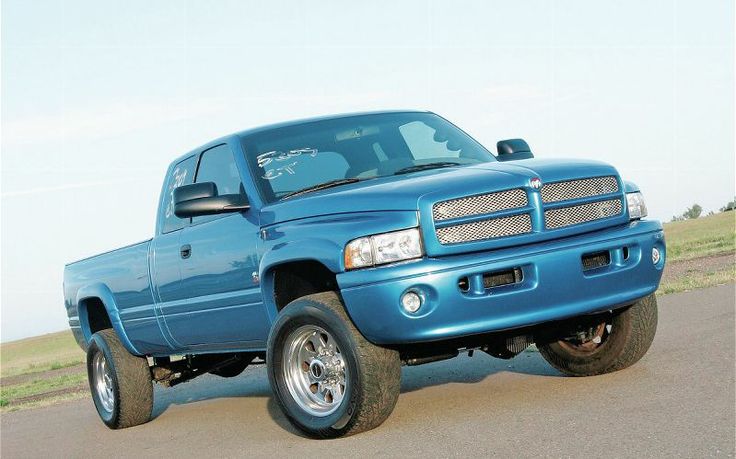 a blue truck is parked on the side of the road in front of some grass