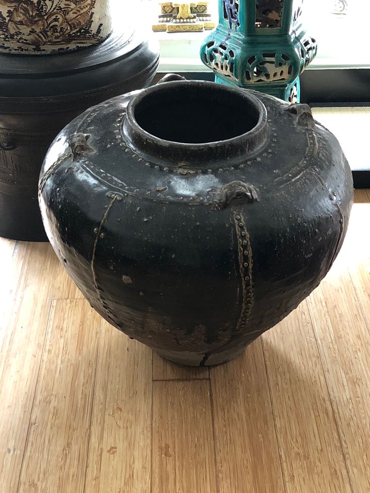 two large vases sitting on top of a wooden floor next to each other in front of a window