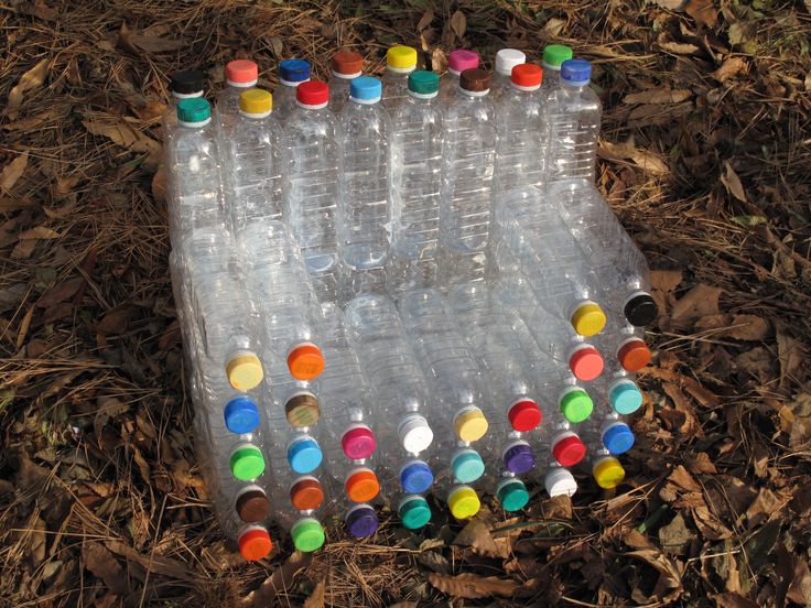 several empty plastic bottles with colored caps on them sitting in the grass and leaves around