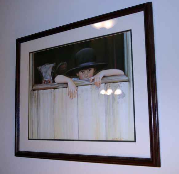 a painting hanging on the wall with a woman's face peeking out from behind a fence