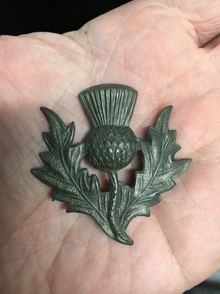 a small metal object in the palm of someone's hand with an acorn design on it