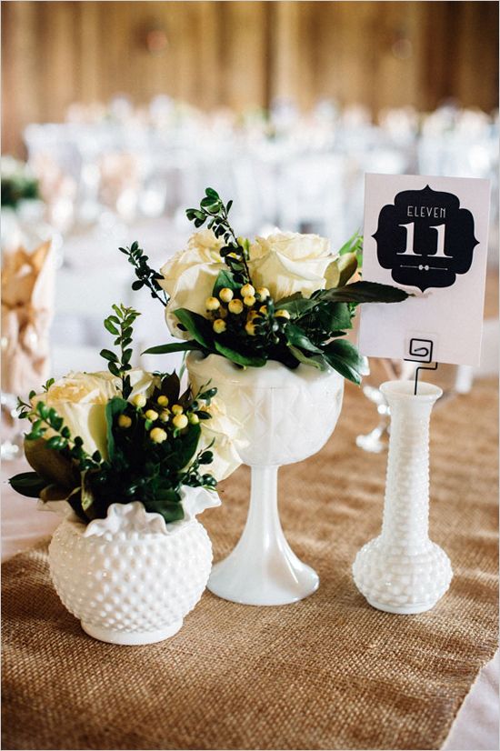 two white vases filled with flowers on top of a table