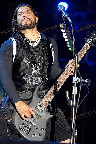 a man with dreadlocks playing an electric guitar on stage at a concert in front of a microphone