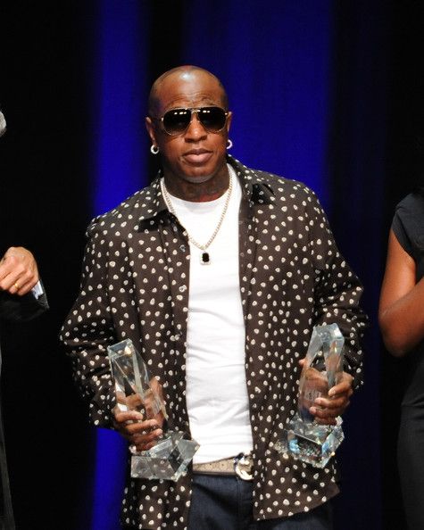 a man holding two awards while standing next to another person on stage at an event