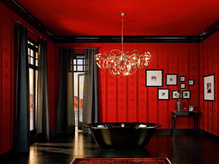 a red room with a black bathtub and chandelier