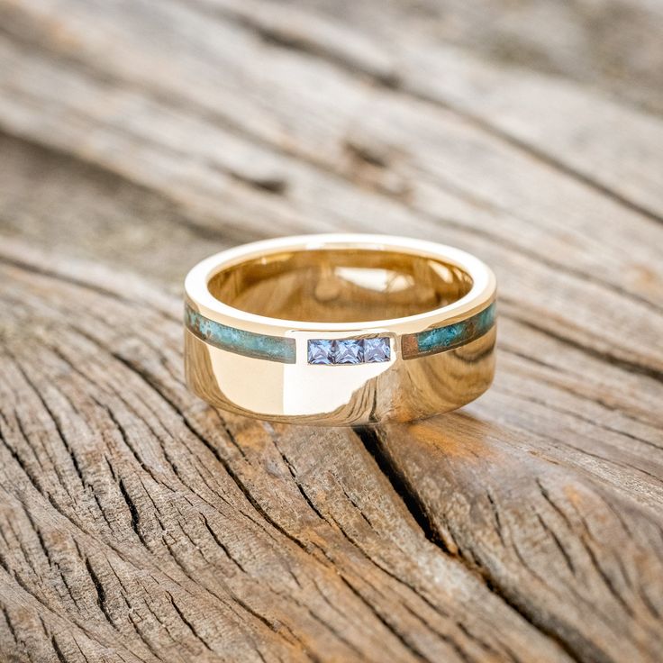 a gold ring with two blue stones on the inside and outside, sitting on a piece of wood