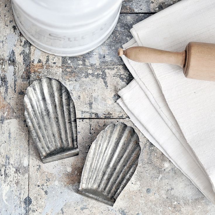 two metal mittens sitting on top of a wooden table next to a white container